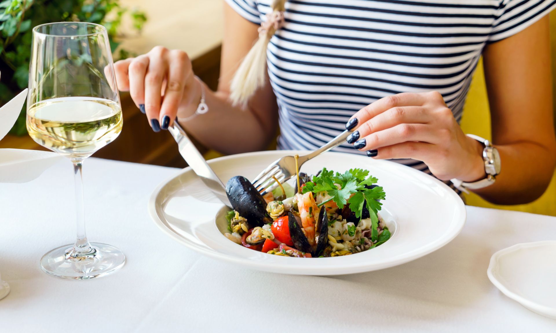 woman eating mussels and pasta dish at restaurant